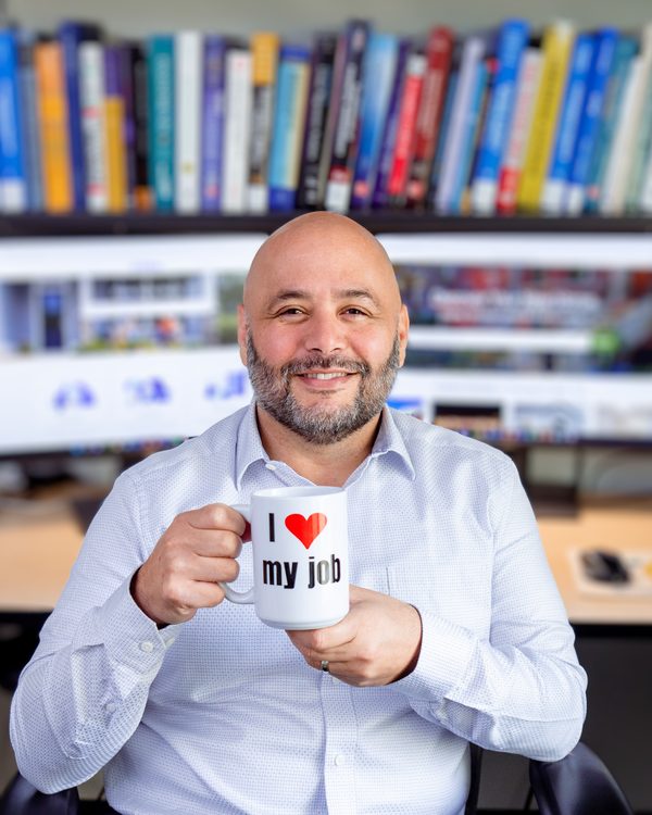 John Garcia in his office, holding an “I love my job” mug